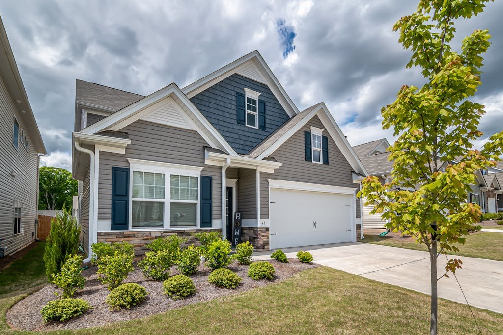 A beautiful suburban house with a manicured garden and cloudy sky, exemplifying modern architecture.